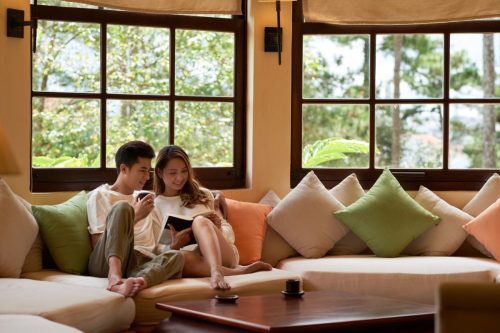 living-room-with-panoramic-windows-romantic-couple-sitting-large-couch-reading-book-together_1098-19315